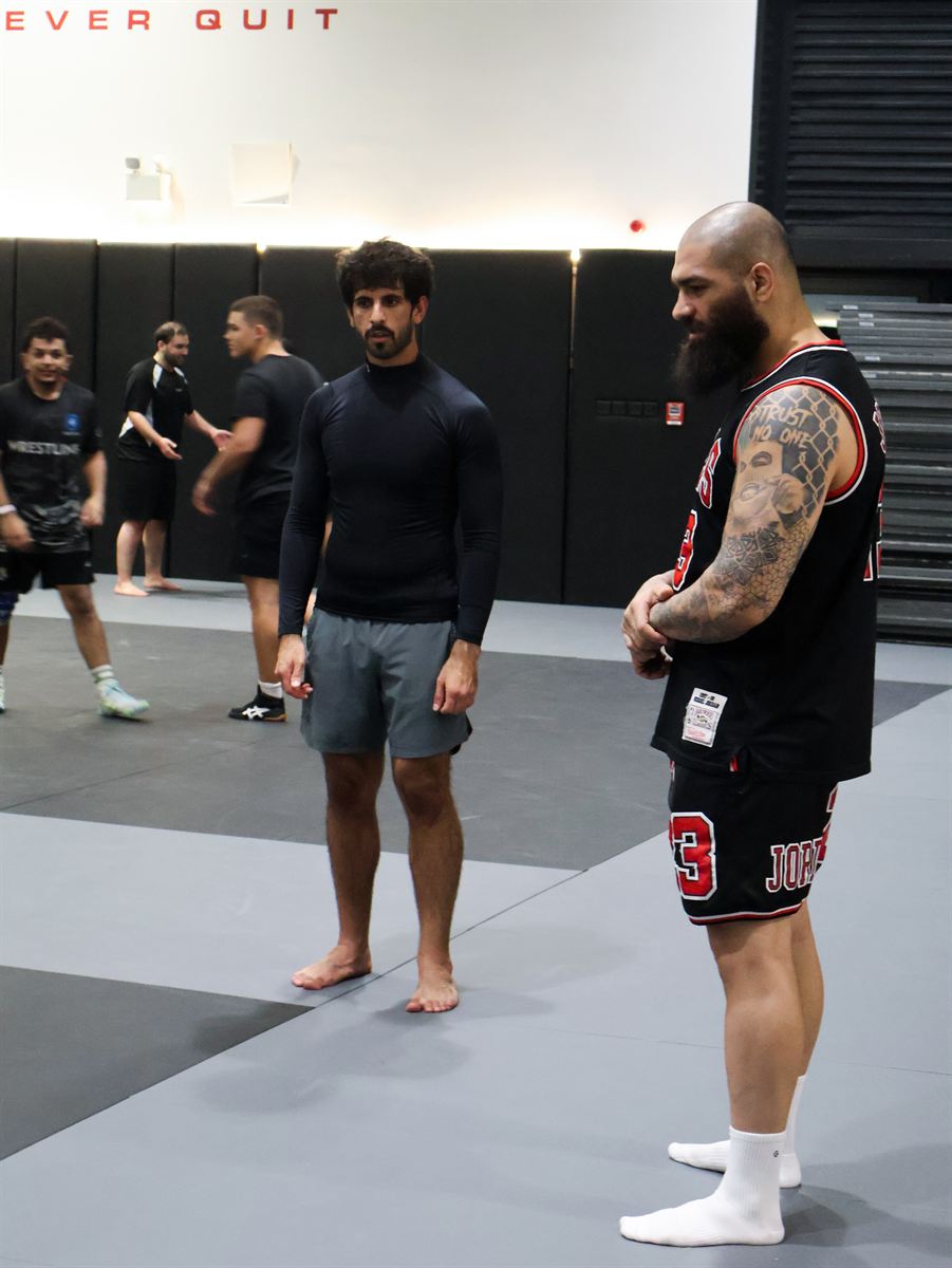 Two athletes squaring up before a round under the Never Quit wall