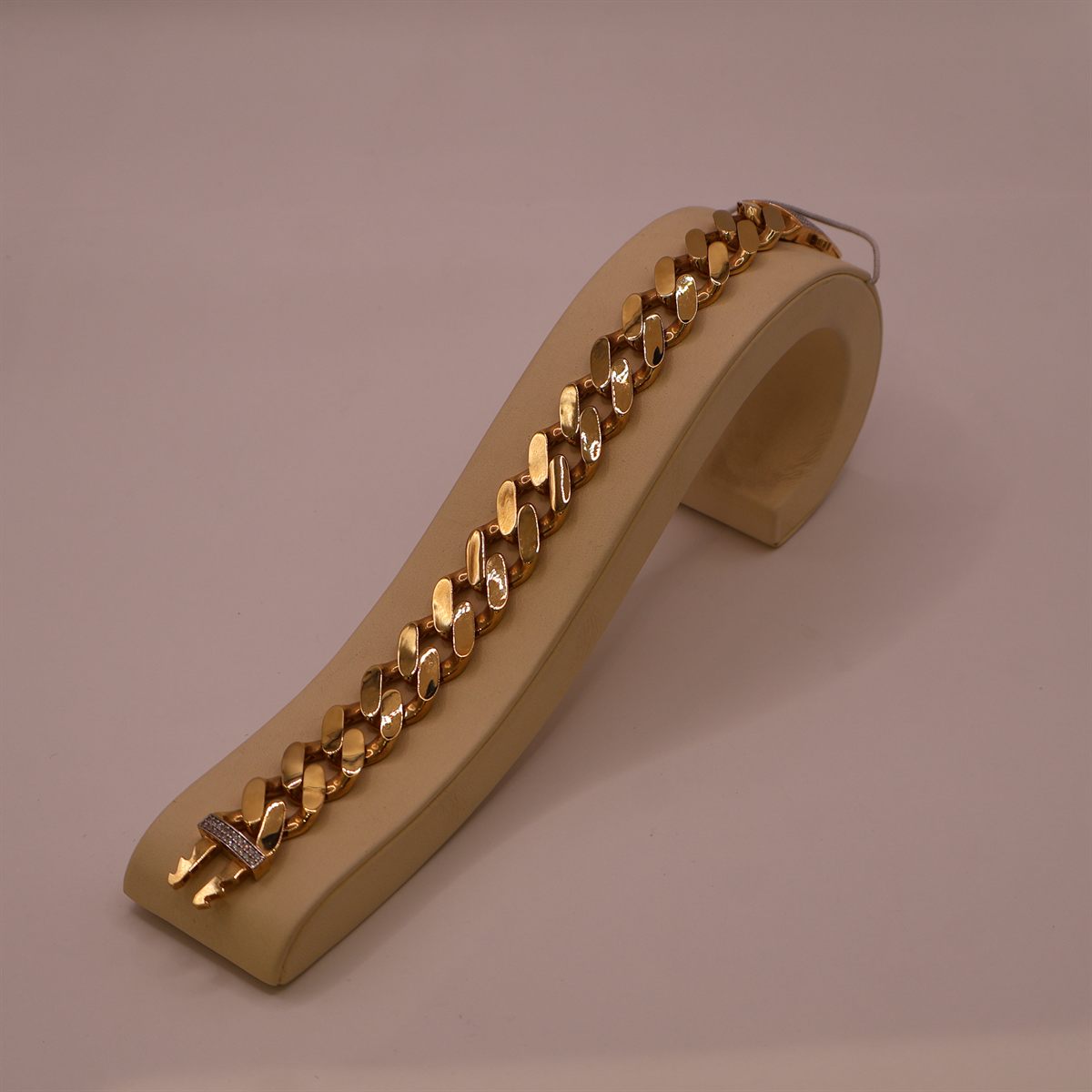 Gold curb-link bracelet laid along a display stand