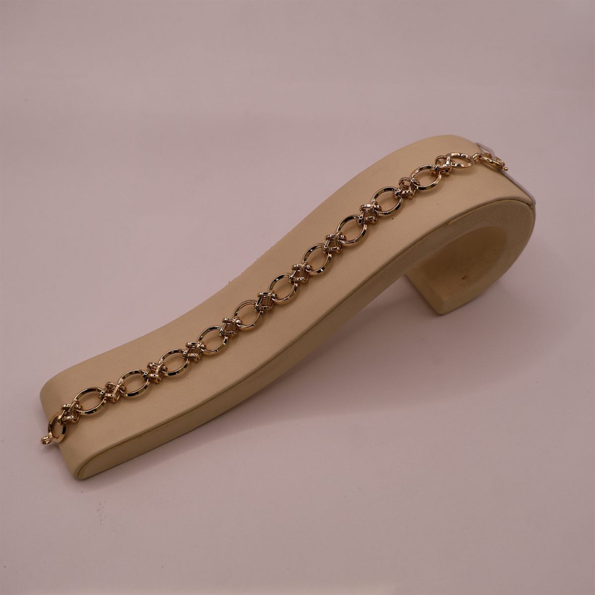 Gold twisted-link bracelet curved over a display stand